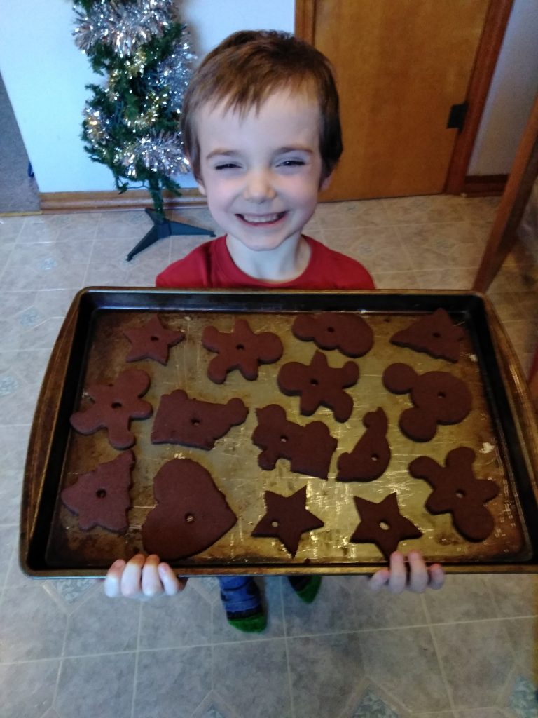 Young child with cinnamon homemade Christmas tree ornaments