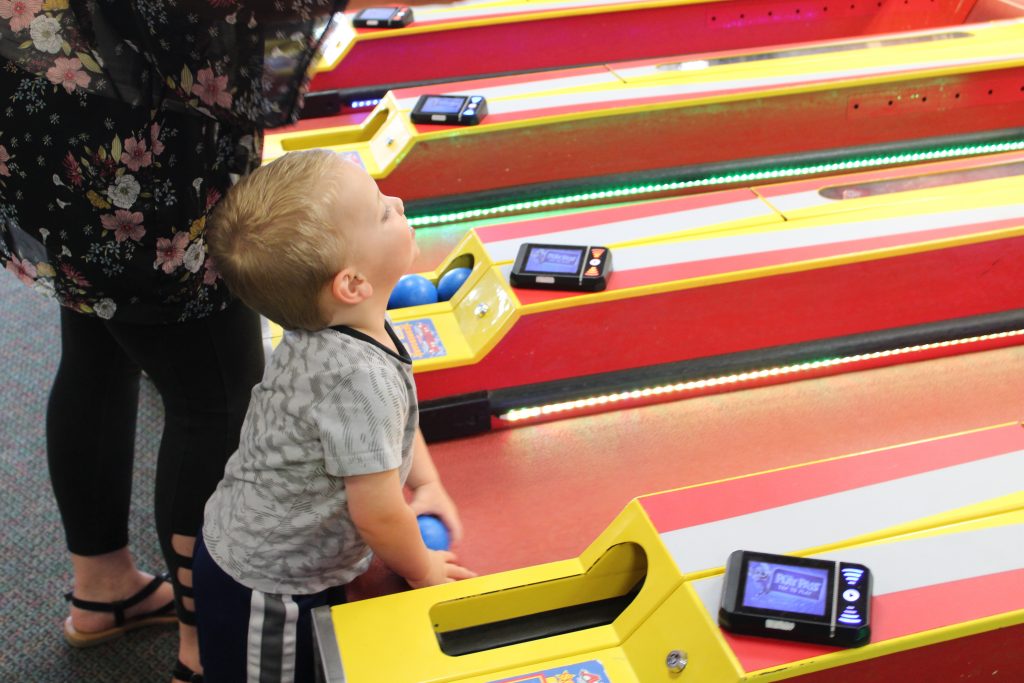 Toddler boy playing skee ball at Chuck E Cheese