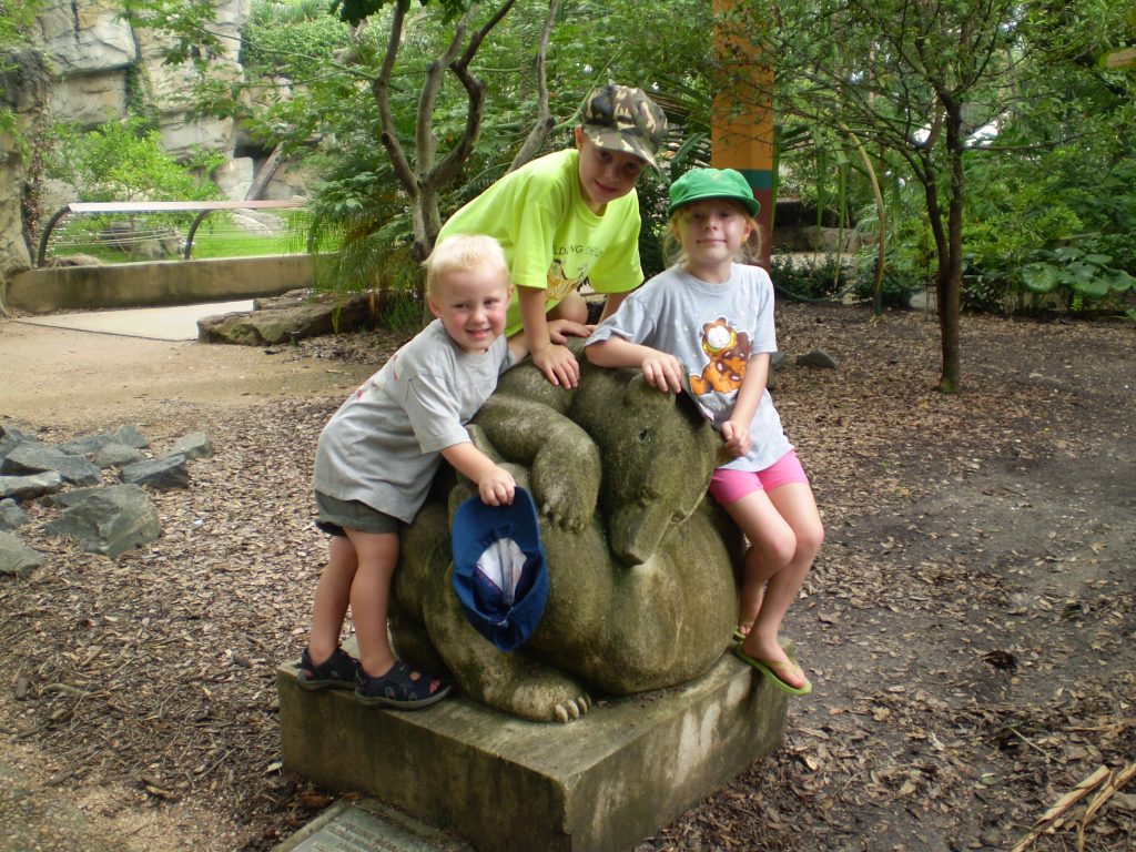 Three young children with statue at the zoo