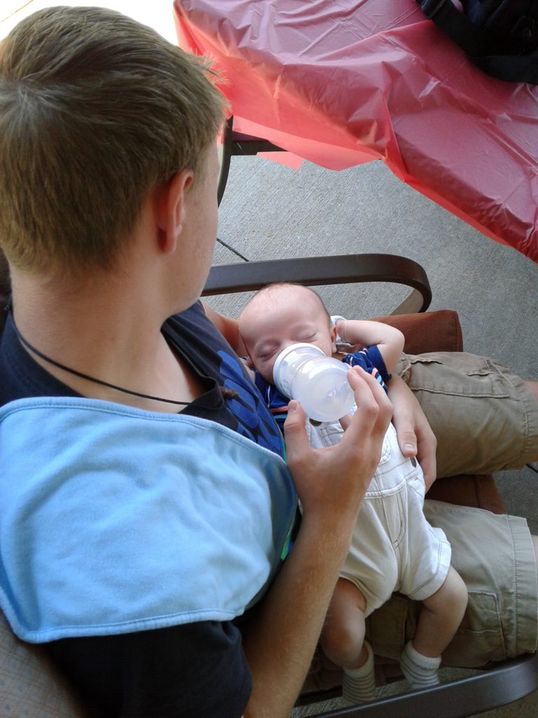 Teen uncle feeding baby with bottle