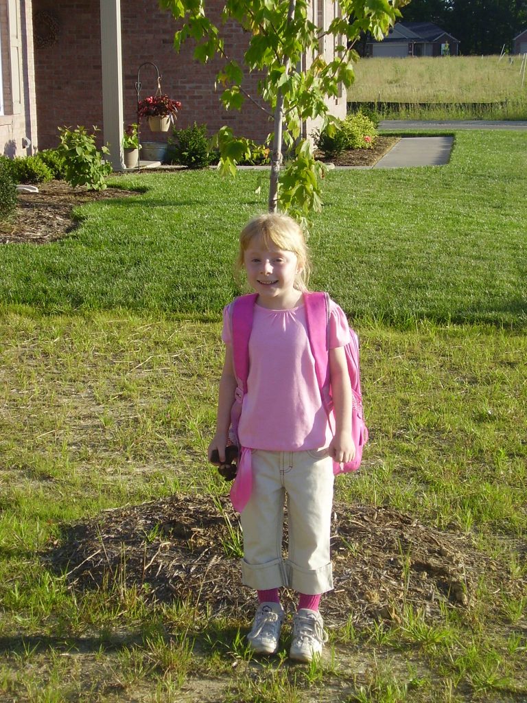 Young girl standing in front of young tree